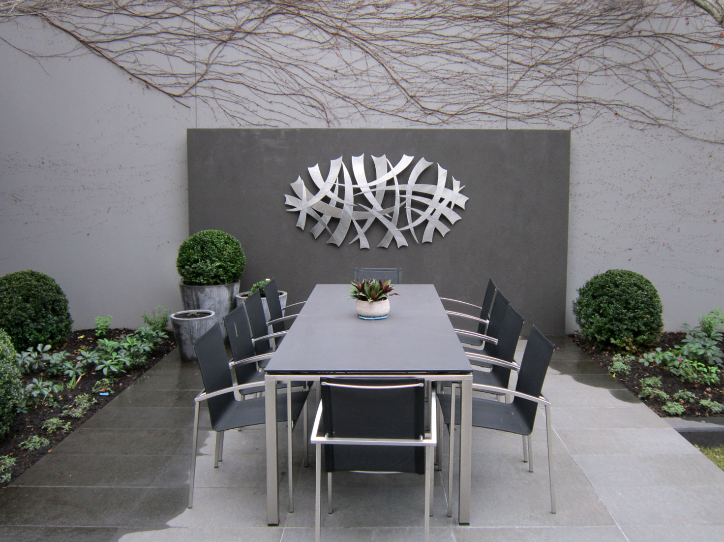 The outdoor dining area with wall feature in the East Melbourne garden designed by Ian Barker Gardens.
